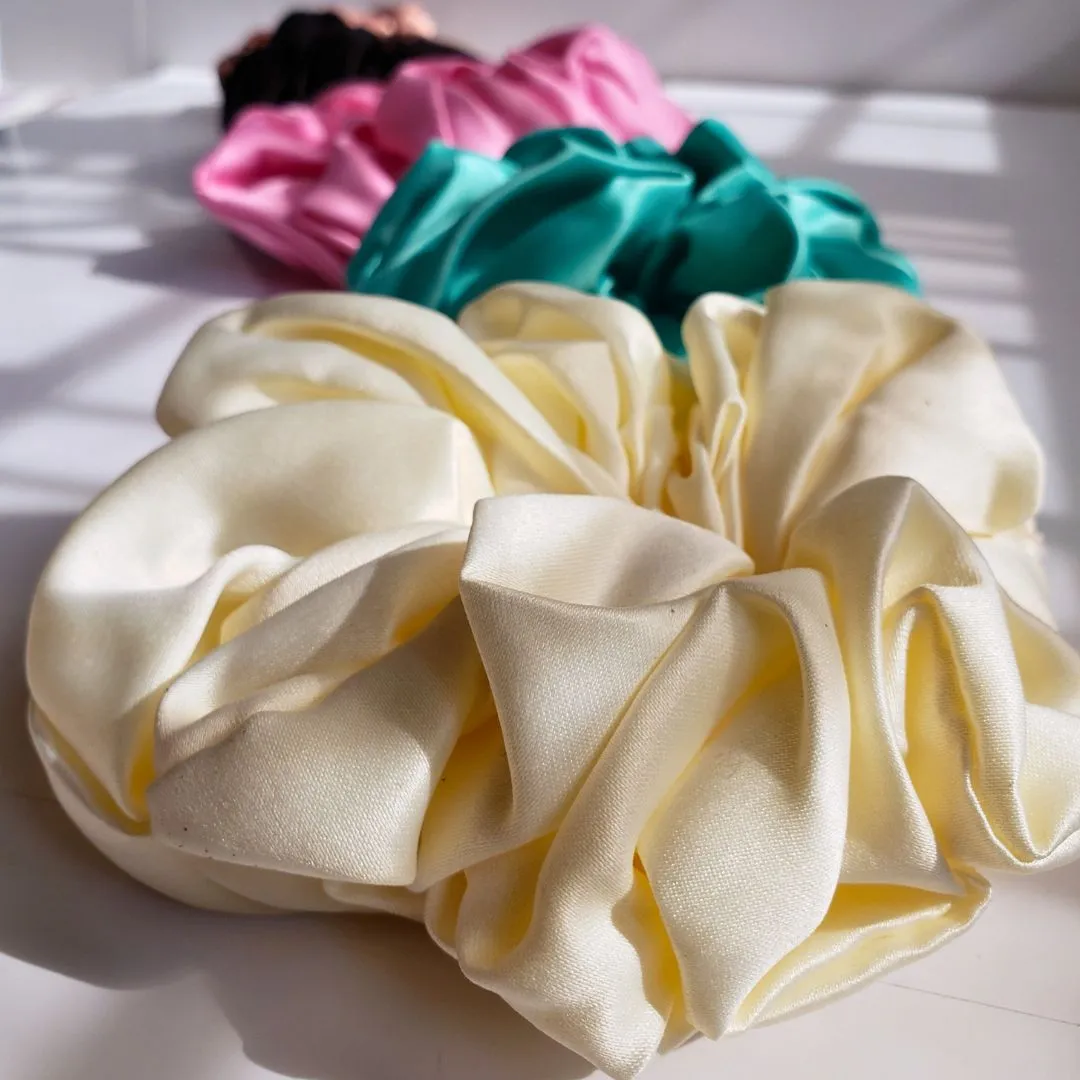 Nuyaé Itunú satin scrunchies in soft elegant colors showing smooth satin texture and gentle elastic hold for natural hair